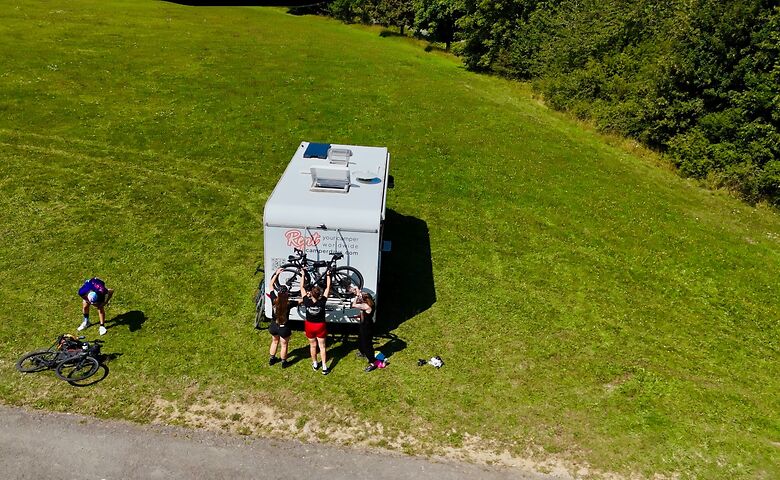 Personen heben Fahrräder auf Wohnmobil