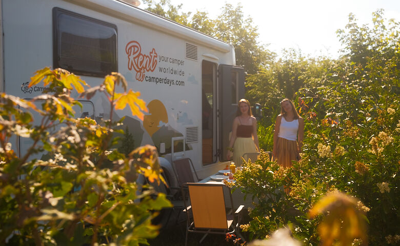 Zwei Frauen stehen auf einem Campingplatz, sanftes Licht und Sommerstimmung