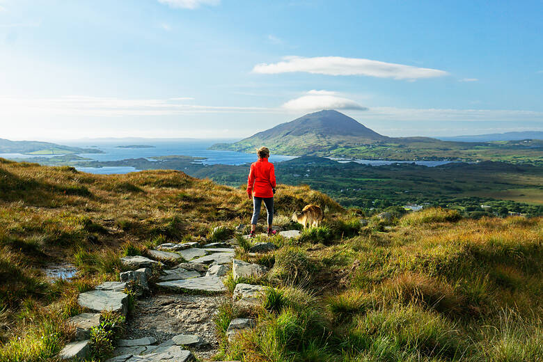 Frau geht in Irland wandern und blickt auf einen Berg 