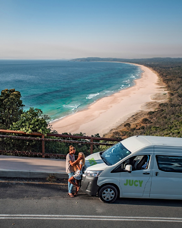 Jucy-Camper parkt auf einer Straße mit Blick auf einen Sandstrand