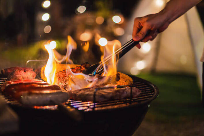 Geld besparen op vakantie - man barbecuet op de camping.