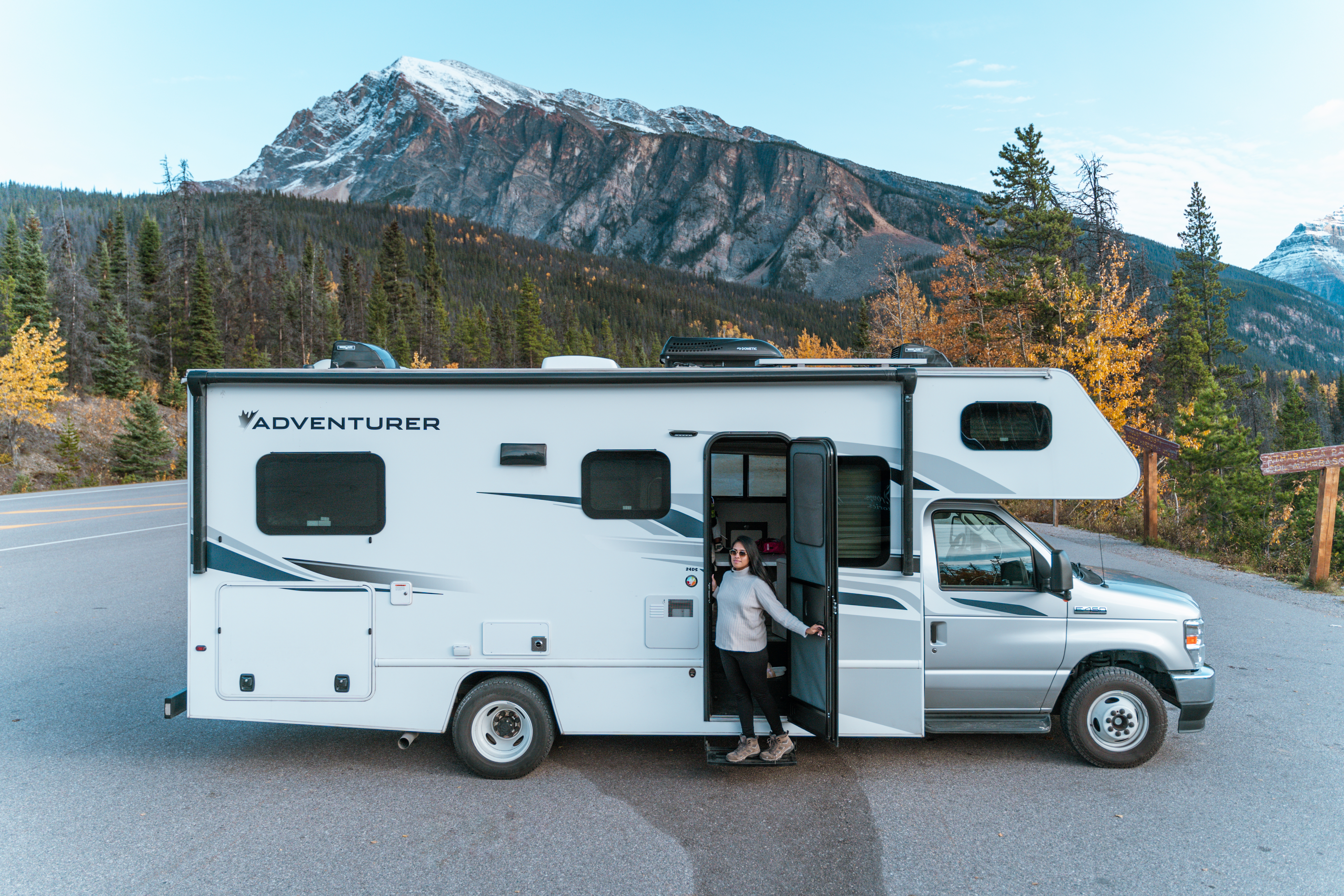 Een persoon staat in de herfst voor een camper in Canada