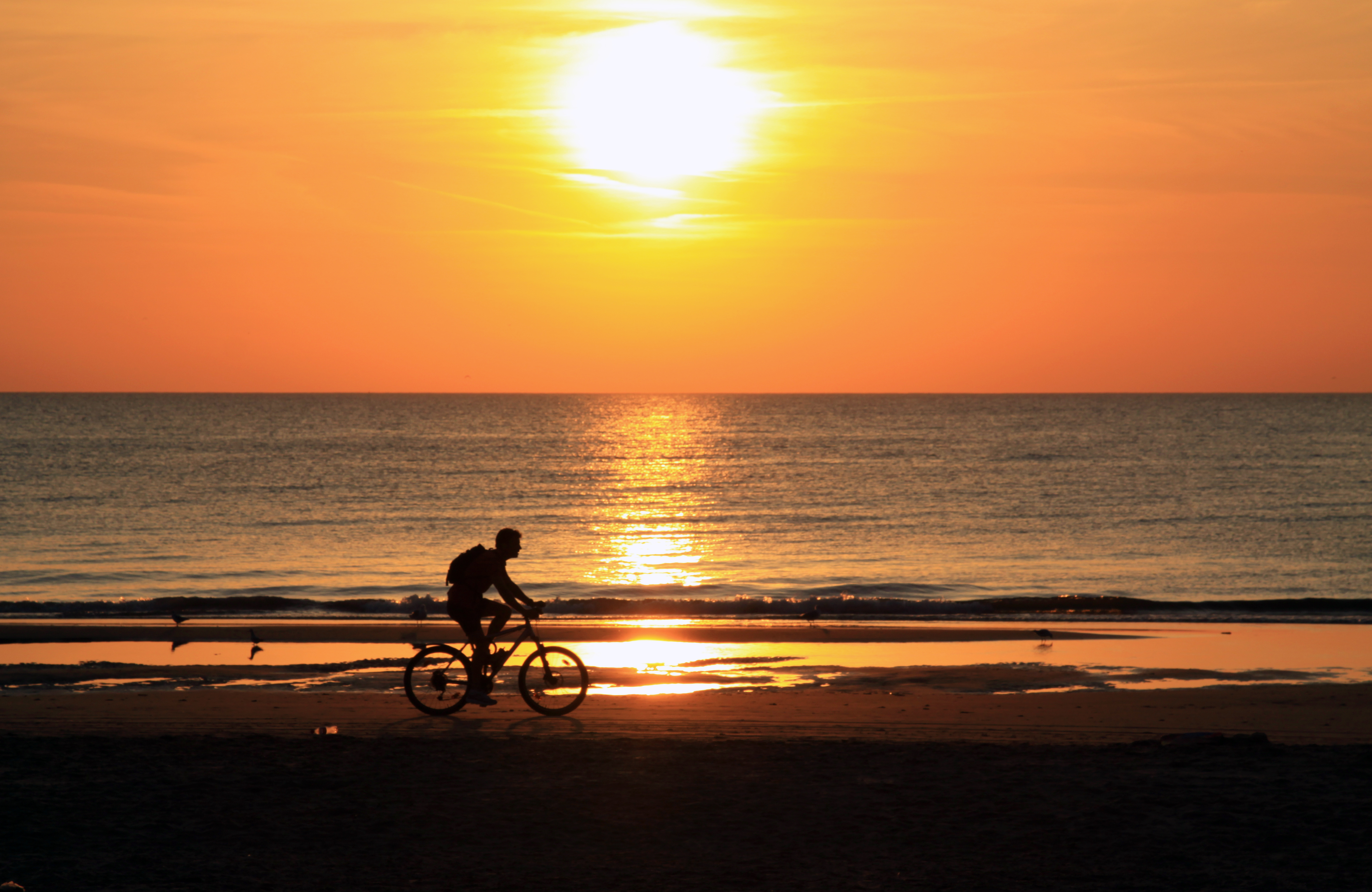Fietsen bij zonsondergang op het strand van Zaandvort