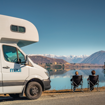 Camper e due persone davanti a un lago