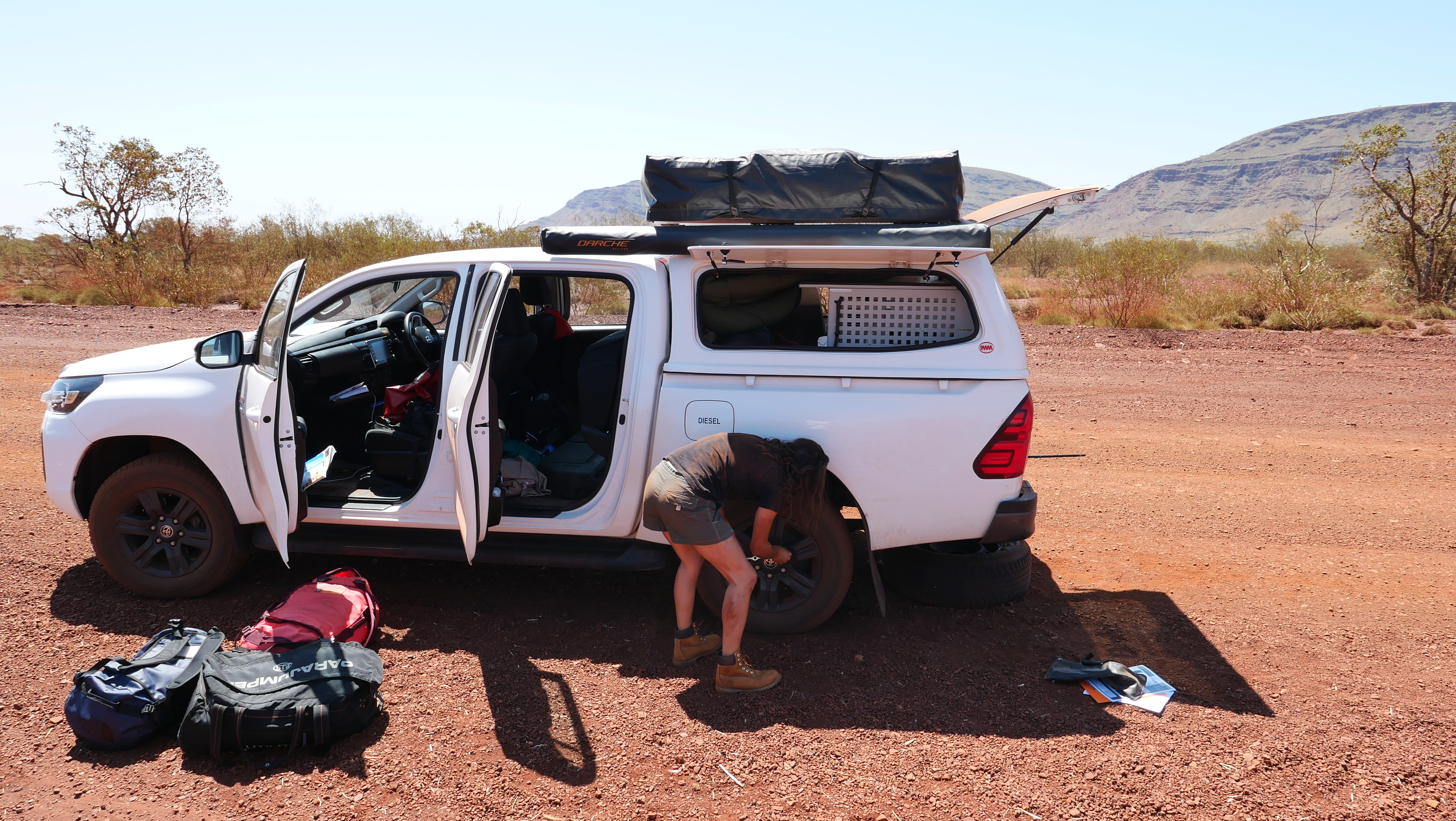 Frau wechselt Reifen am Camper aus 