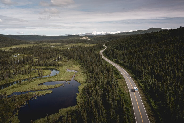 Wohnmobil fährt durch die Wälder Alaskas mit Blick auf die Berge