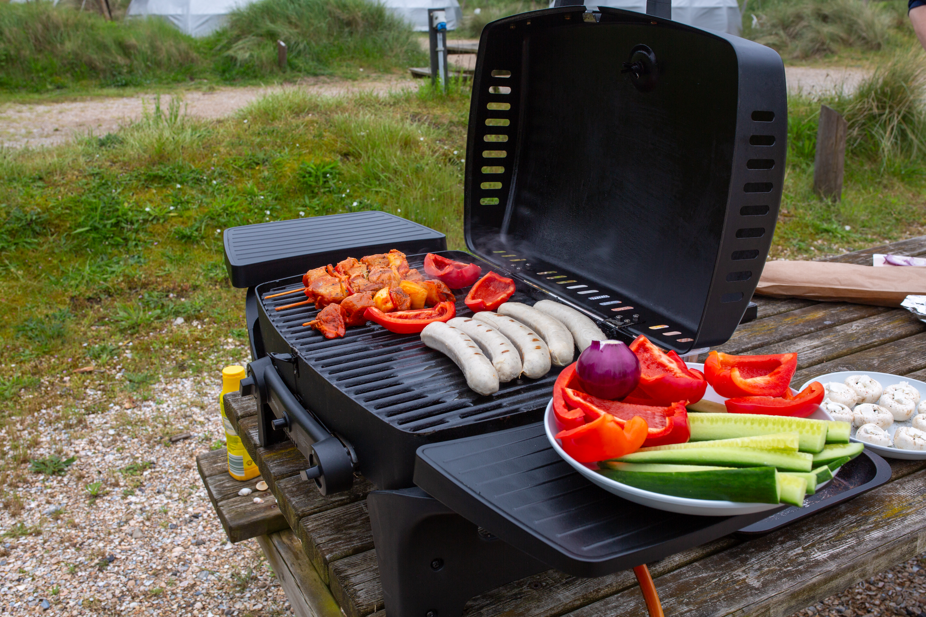 Gasgrill mit Gemüse und Würstchen auf dem Campingplatz
