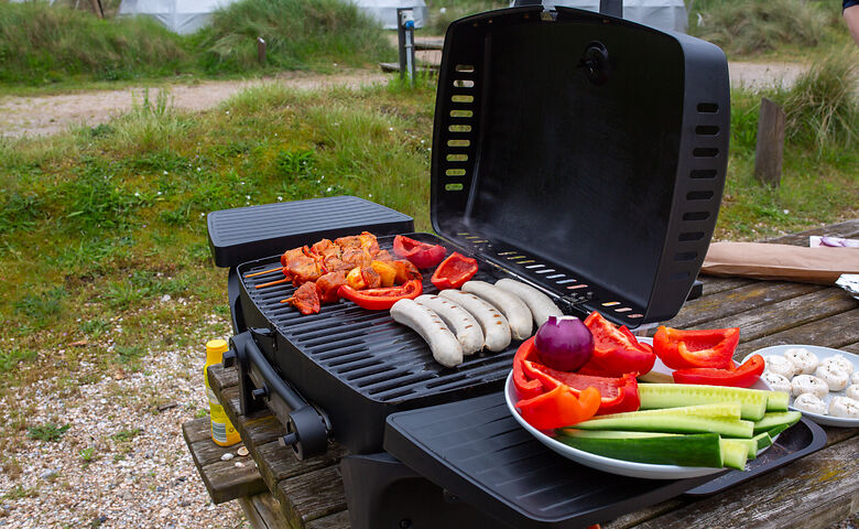 Gasgrill mit Gemüse und Würstchen auf dem Campingplatz