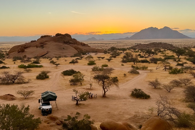Camper mit Dachzelt in der namibischen Wüste bei Sonnenuntergang 