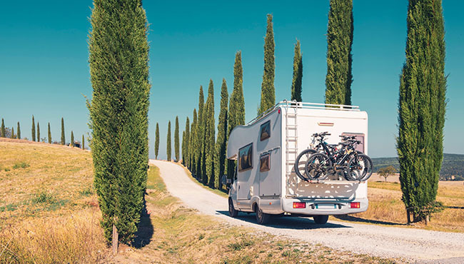 Ein Wohnmobil fährt durch eine Allee in der beliebten Region Toskana in Italien.