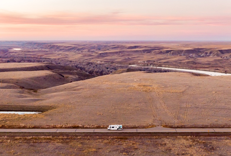 Wohnmobil fährt durch eine weite kanadische Landschaft bei Sonnenaufgang