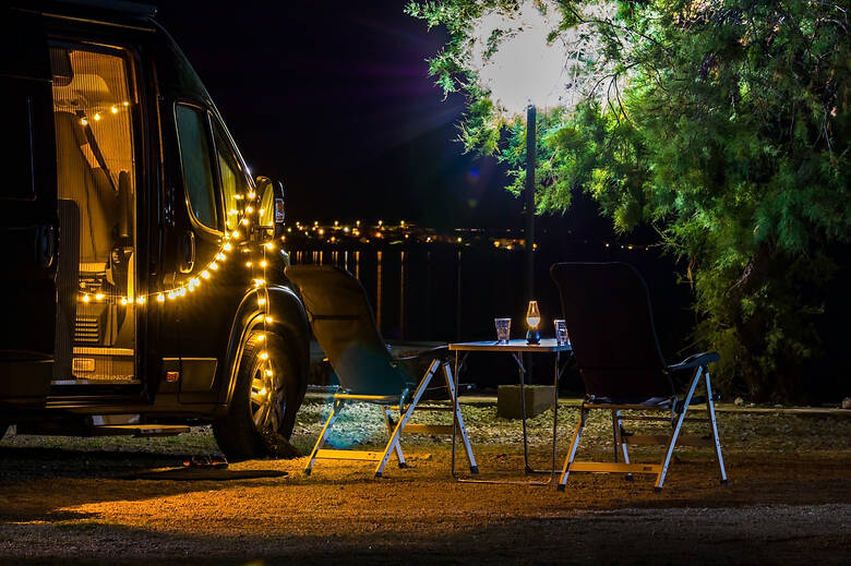 Camper mit Lichterkette an einem Strand 