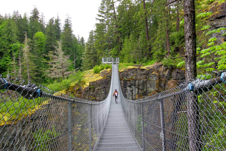 Frau überquert Hängebrücke im Elk Falls Provincial Park in Kanada