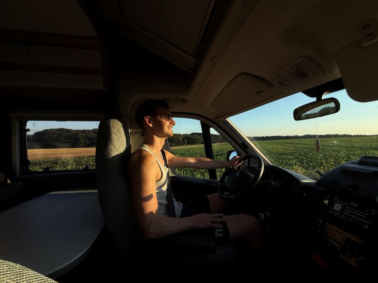Mann fährt an einem sonnigen Tag mit dem Wohnmobil in den Urlaub 