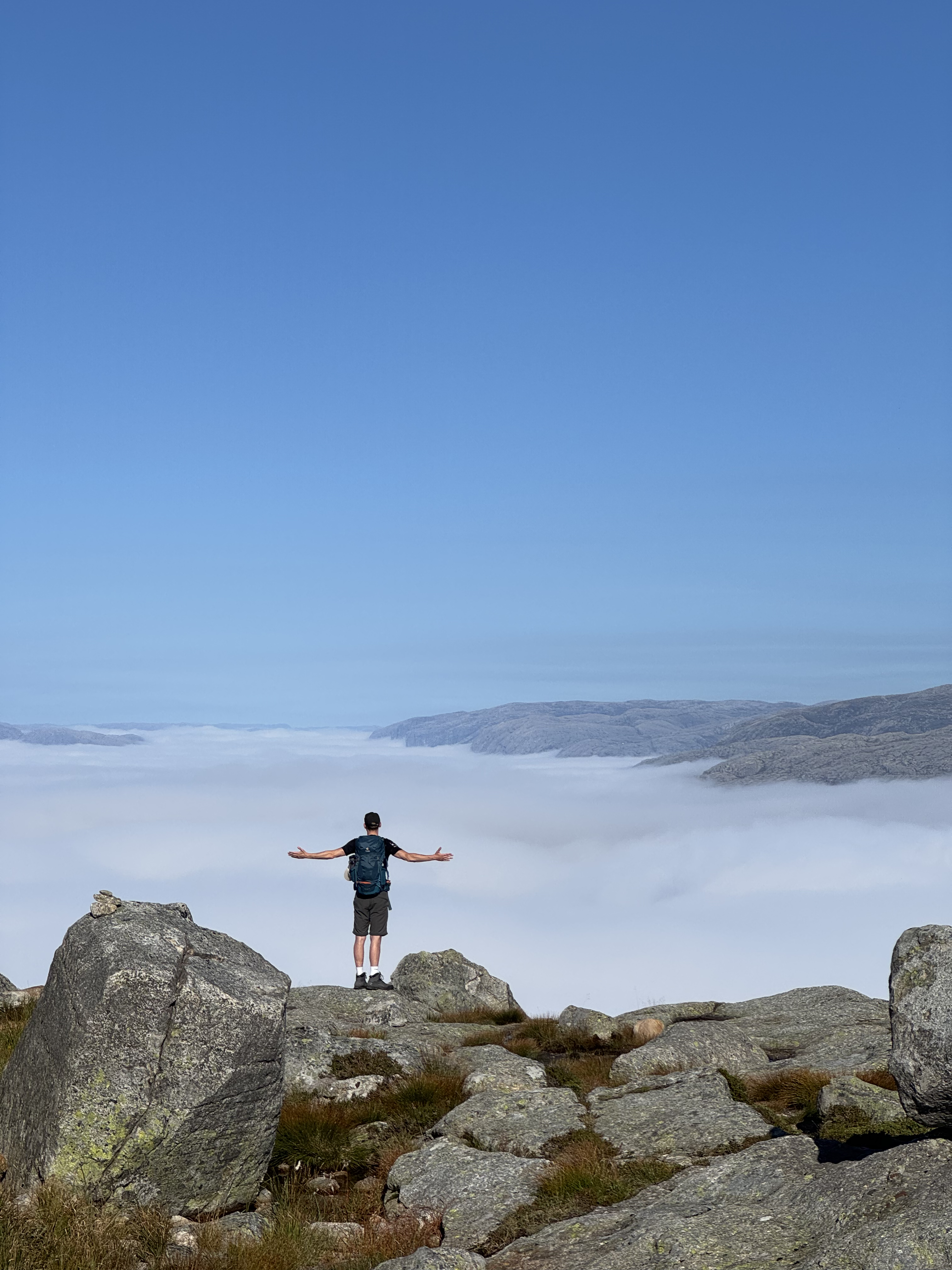Mann auf dem Preikestolen in Norwegen schaut auf eine Wolkendecke