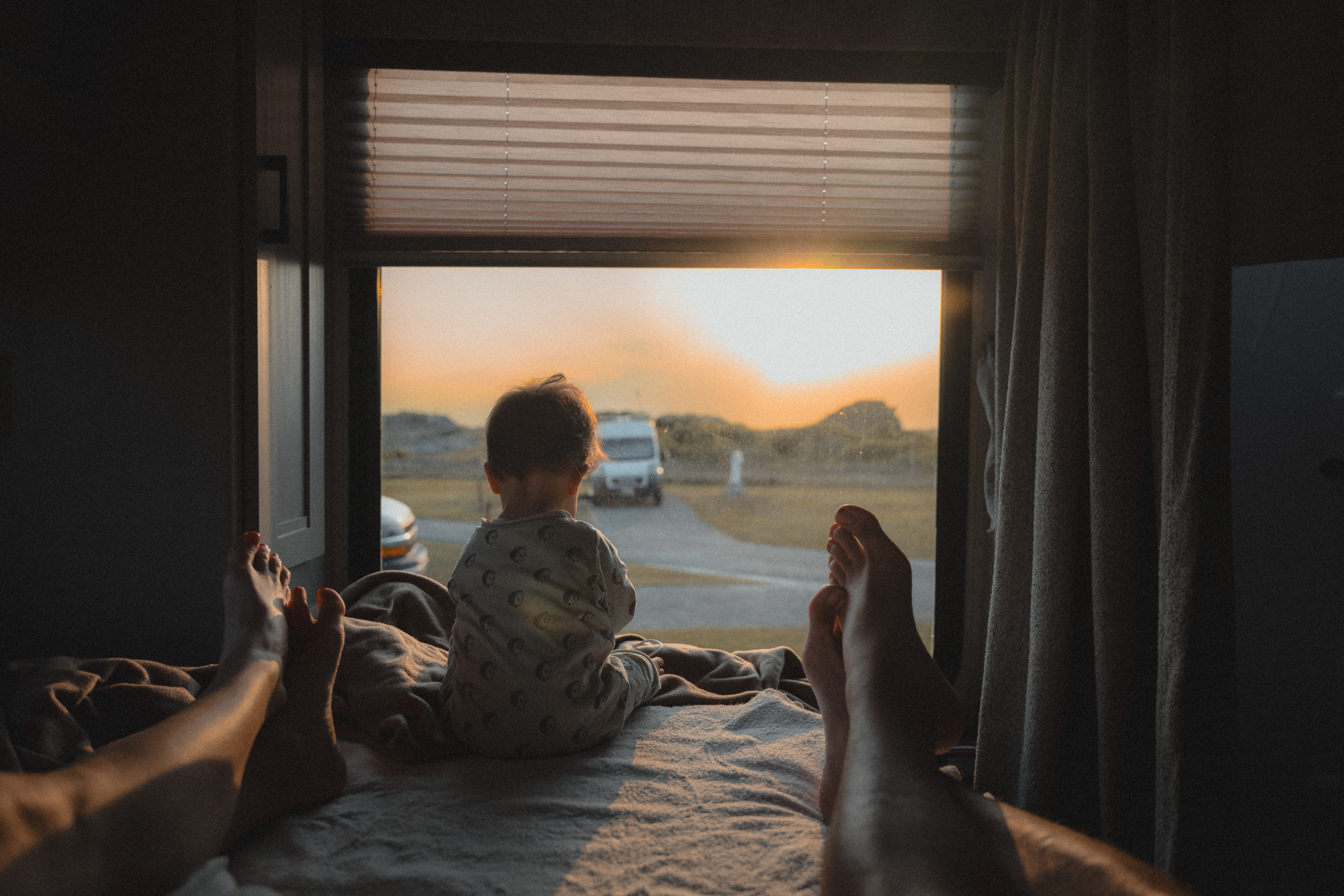 Niño sentado en una autocaravana con vistas al mar.