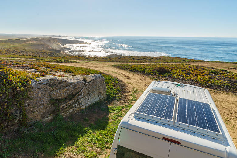 Camper mit Solarplatten auf dem Dach am Meer