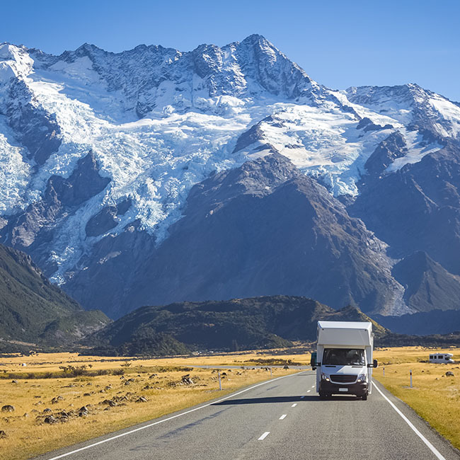 Ein Wohnmobil fährt entlang einer Straße durch eine wunderschöne Naturkulisse in Neuseeland