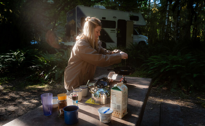 Frau bereites Essen auf dem Campingplatz zu