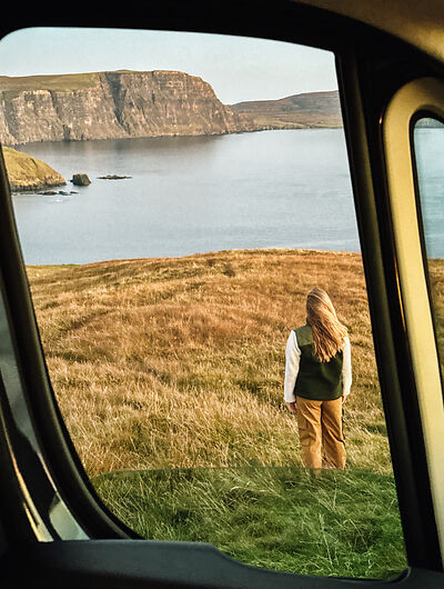 Mujer mirando los acantilados de Escocia y el mar