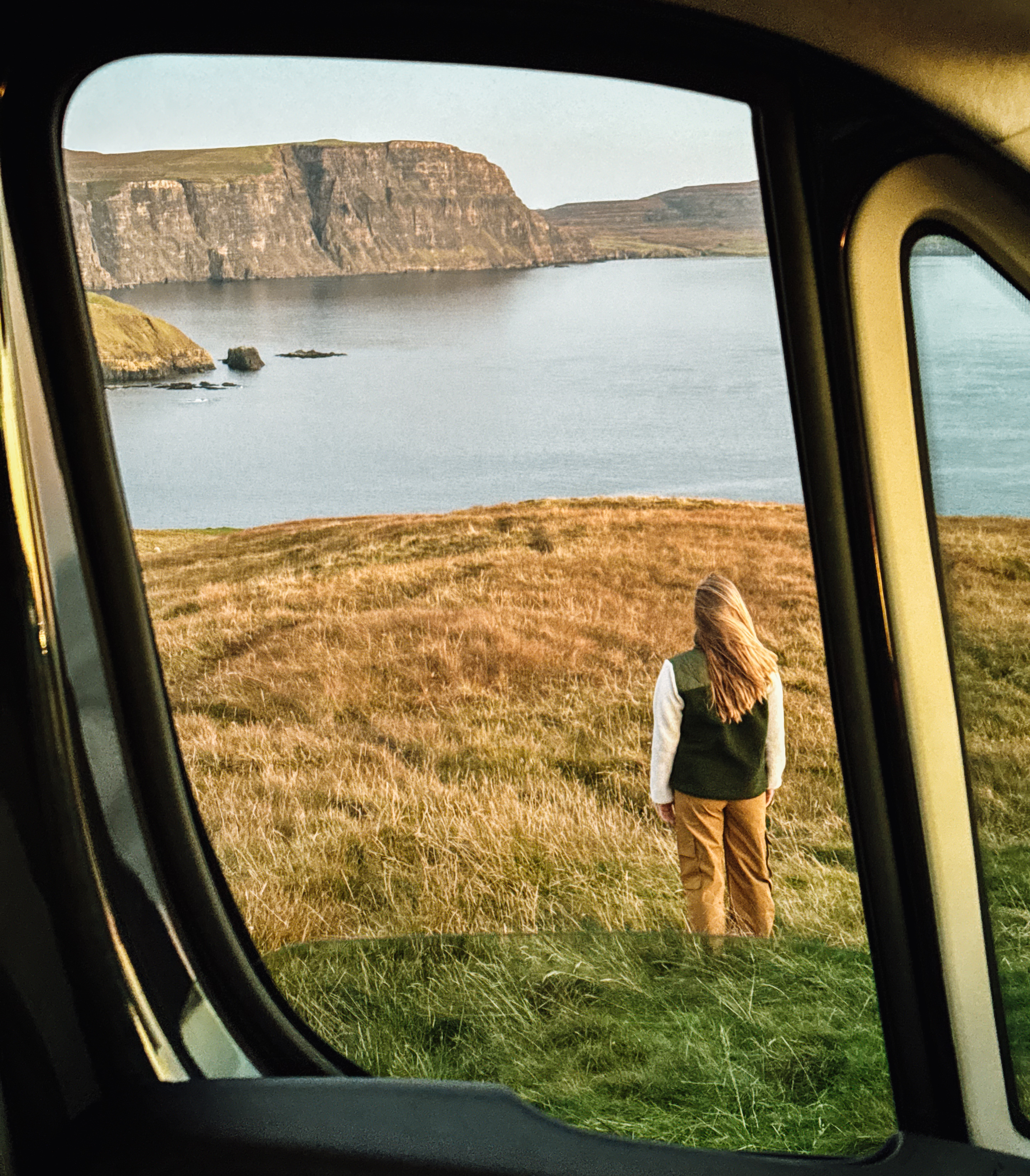 Mujer mirando los acantilados de Escocia y el mar