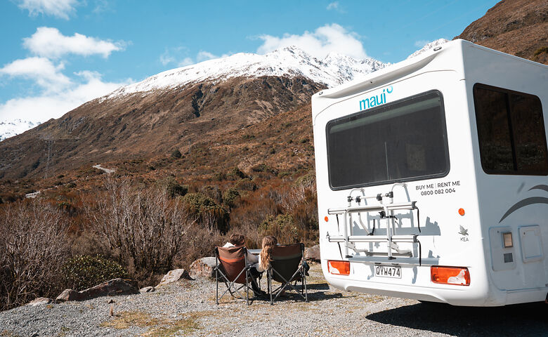  Paar in Camping-Stühlen neben dem Wohnmobil in Neuseeland 