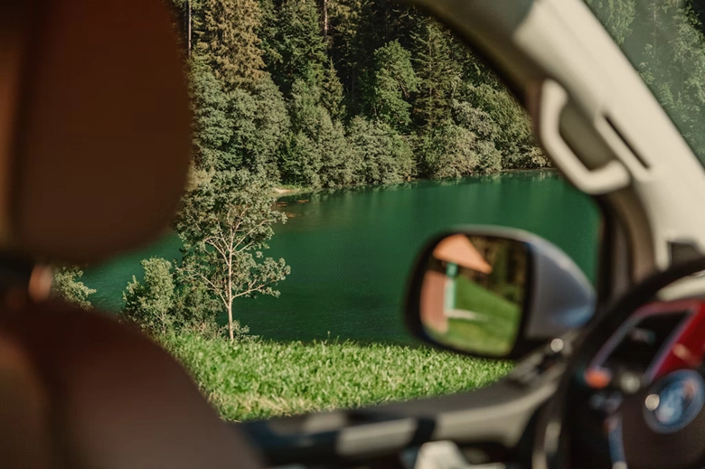 Frau schaut aus dem Camper auf einen blauen Bergsee in der Schweiz