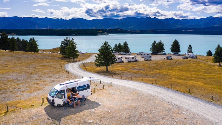 Junge Menschen campen an einem See in Neuseeland mit Blick auf die Berge 