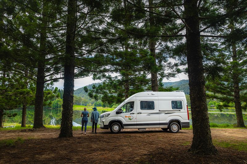 Camper und zwei Personen in einem Wald 