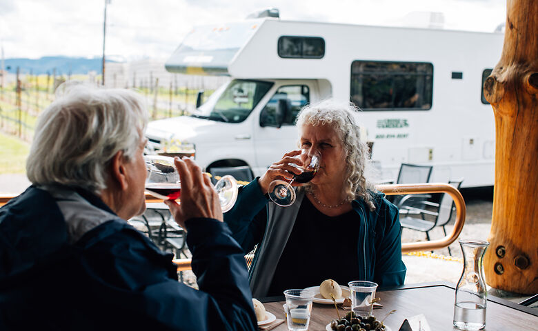 Senioren trinken ein Glas Wein vor dem Wohnmobil