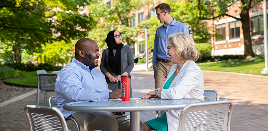Four diverse Lilly employees talk outside in the courtyard