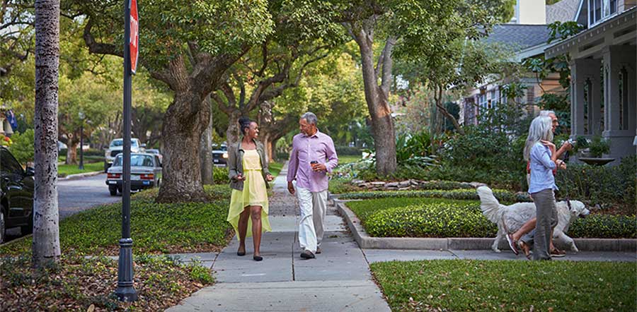 four people walking on the sidewalk in a residential neighborhood