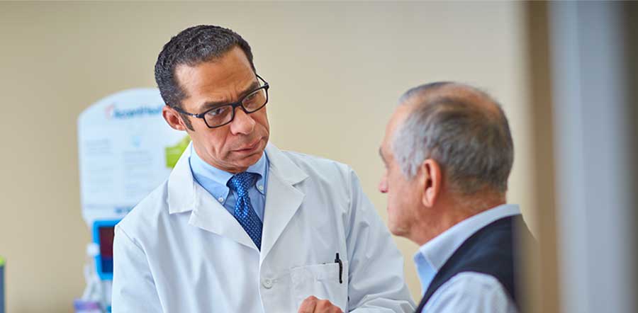 doctor talking to elderly male patient in exam room