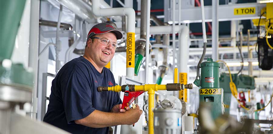 man smiling and holding lever in manufacturing