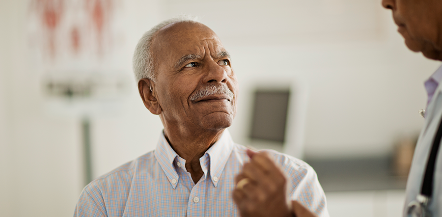 Black man with white hair looking at doctor offcamera