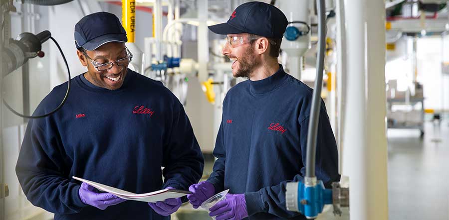 two people smiling looking at paper in manufacturing