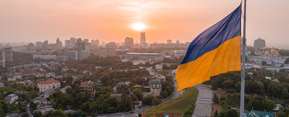 Ukraine flag flying over Kyiv at sunset