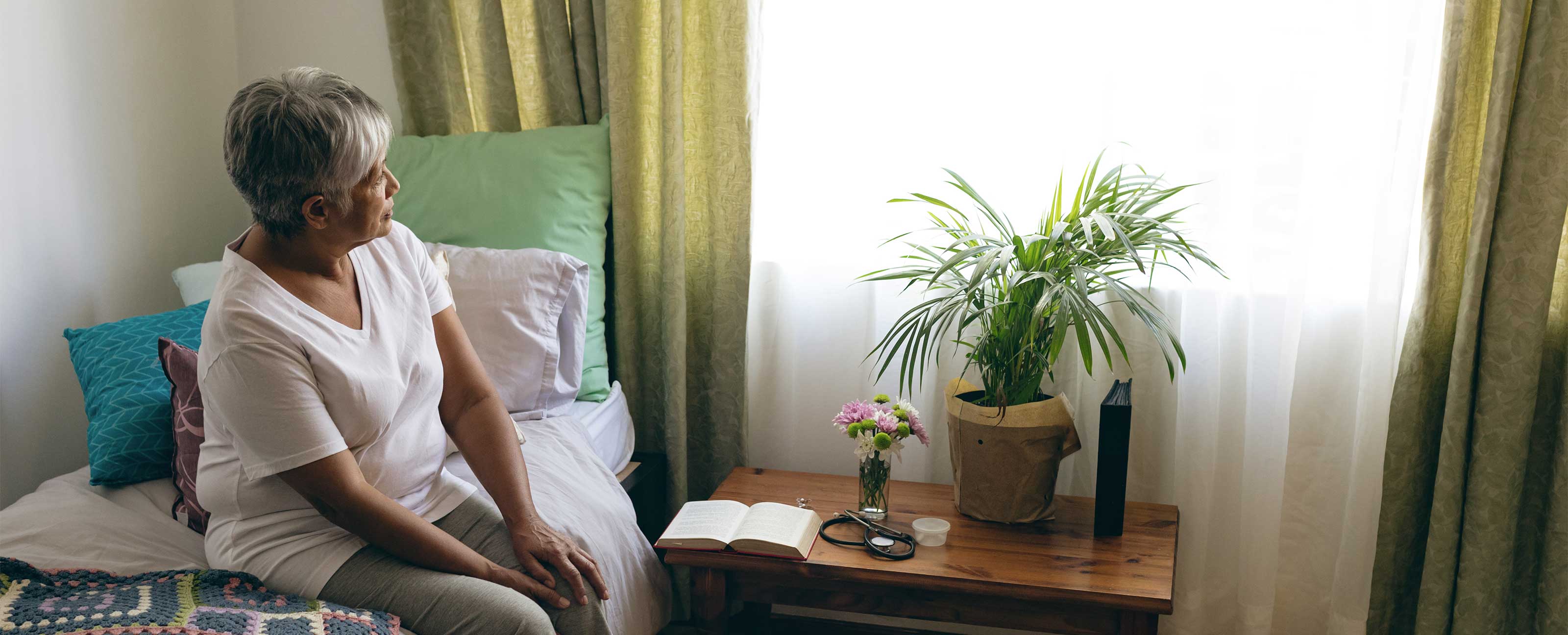 woman sitting on bed looking out window