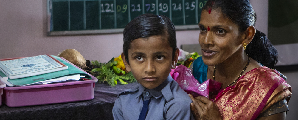 A boy is sitting with a woman.