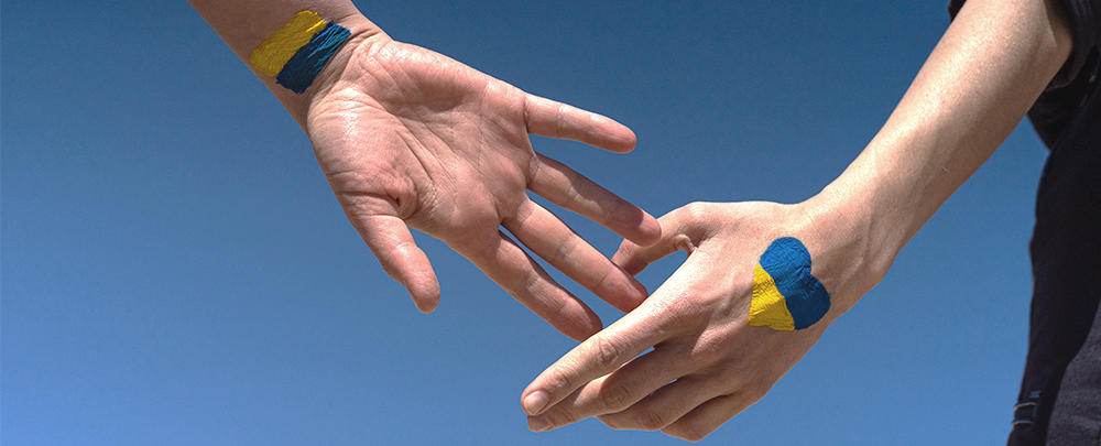 two hands come together with Ukrainian colors painted on them