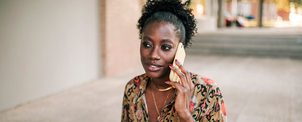 black woman walking and talking on cell phone