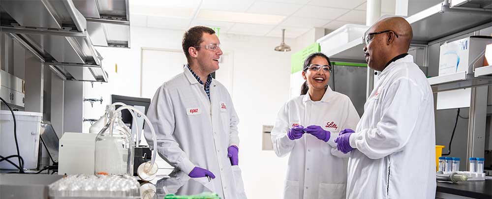 three Lilly scientists talking in a lab