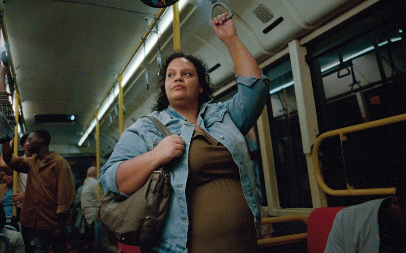 穿着牛仔夹克和绿色连衣裙的女性站在公交车或地铁上。