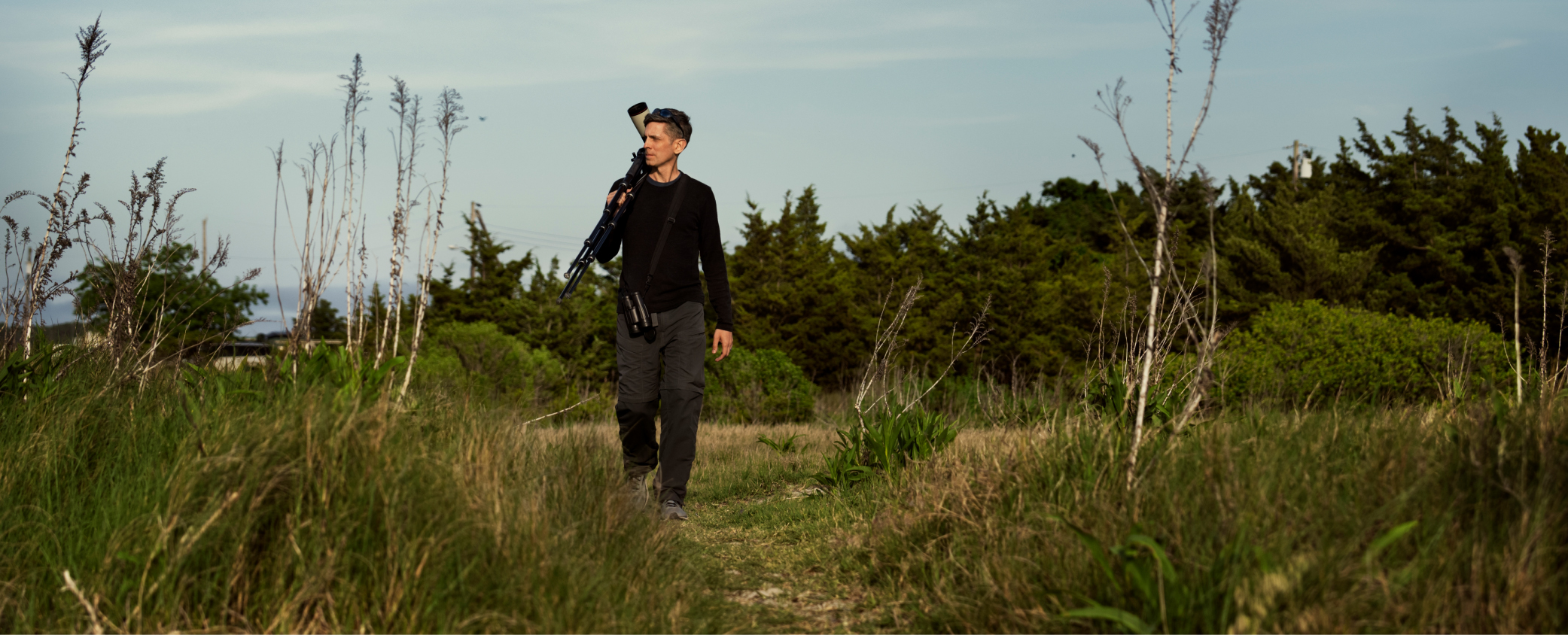 Scientist Jay Bolden walking through a coastal shoreline with greenery