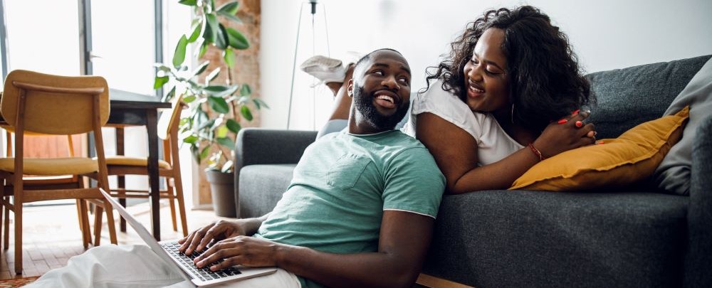 Black male and female laying in living room smiling at each other