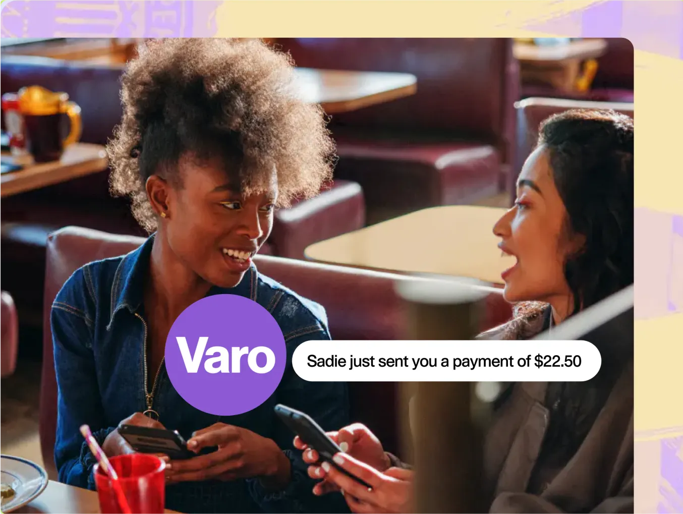 Varo advertisement featuring two women sitting in a café, smiling and looking at their smartphones. A notification bubble reads, 'Sadie just sent you a payment of $22.50.' The Varo logo is prominently displayed in a purple circle. The background includes a cozy café setting with tables and booths.