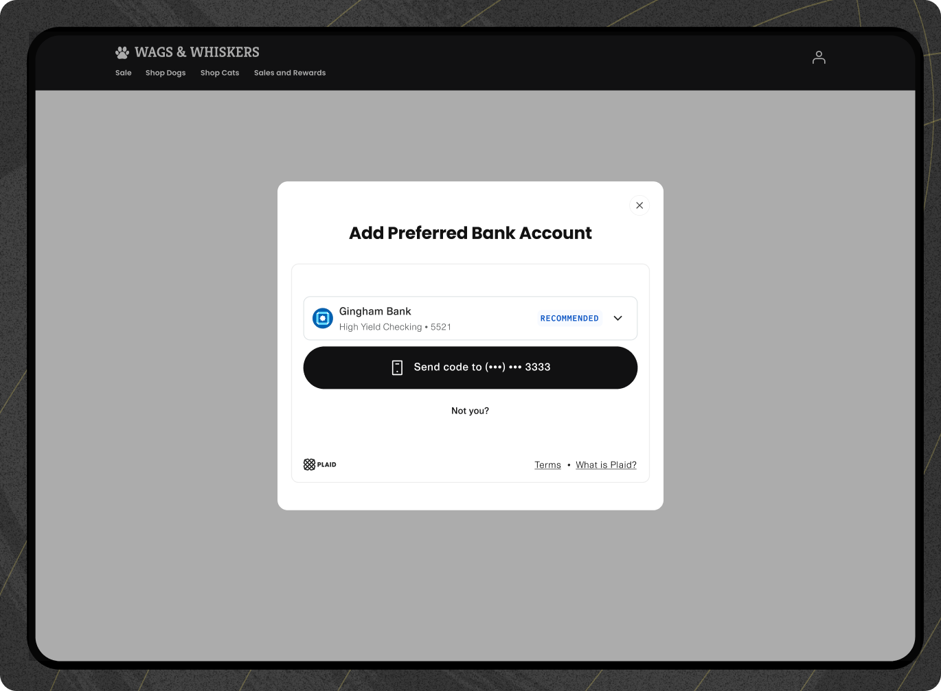 Popup window on the Wags & Whiskers website displaying an option to 'Add Preferred Bank Account.' The Gingham Bank High Yield Checking account ending in 5521 is selected and labeled as 'Recommended.' Below, a button prompts to 'Send code to (•••) ••• 3333.' Links to 'Terms' and 'What is Plaid?' are shown at the bottom of the popup. 