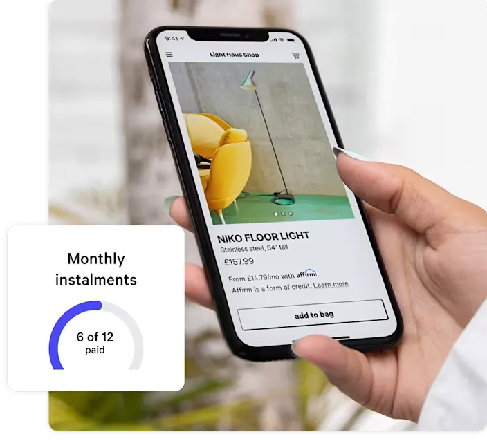 Close-up of a person's hand holding a smartphone displaying an online shopping app. The screen shows a product listing for a 'Niko Floor Light' priced at £157.99, with financing options available through Affirm. In the bottom left corner, a progress tracker indicates '6 of 12 monthly installments paid' in a circular graphic.