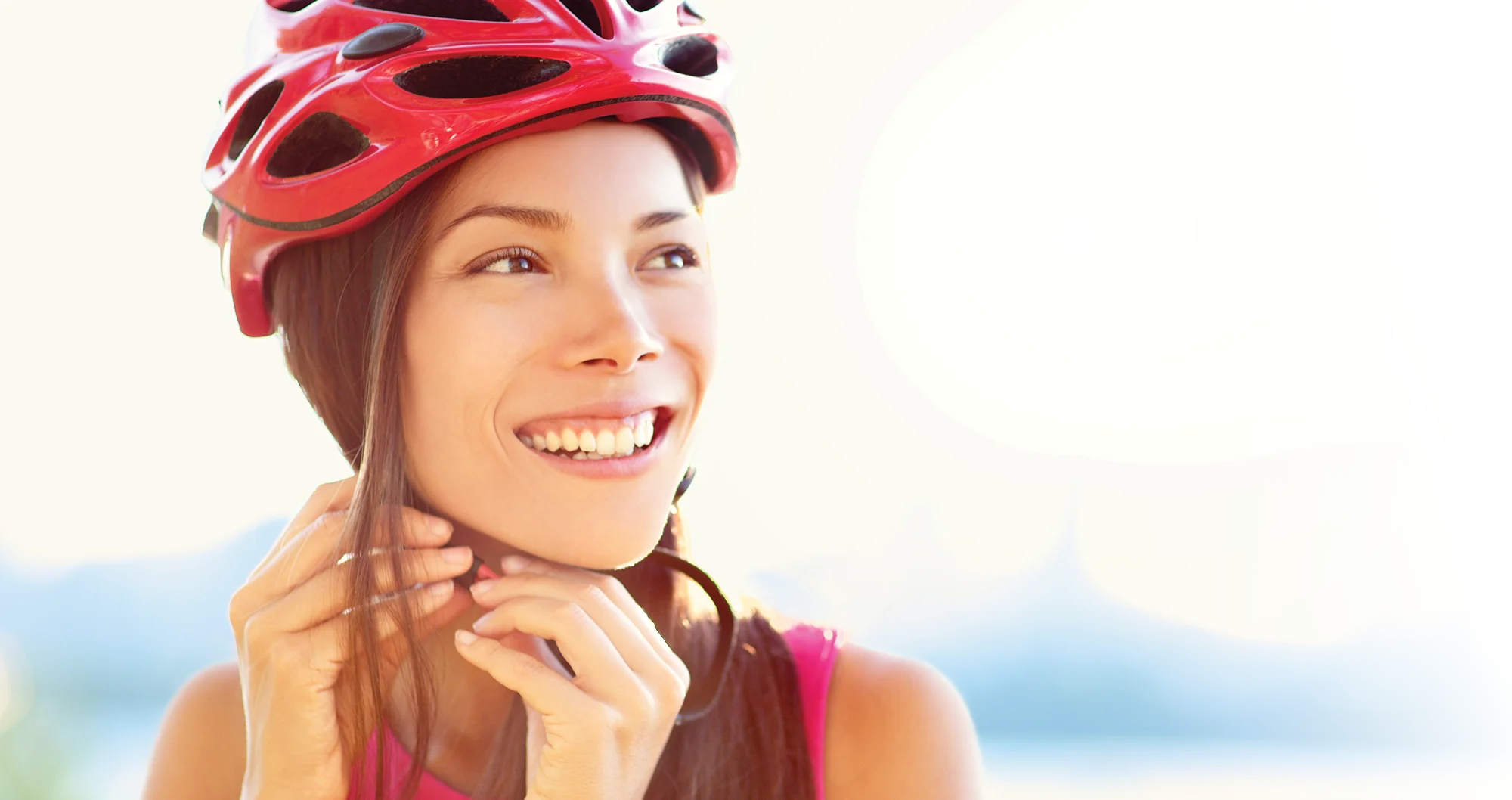 Femme souriante, serrant son casque alors qu’elle se prépare pour une promenade à vélo.