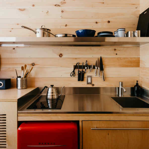 Getaway cabin kitchen with pots, stove, kettle, cookware, sink, refrigerator, and more.